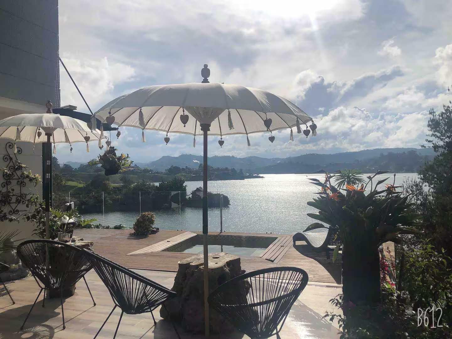 Terraza privada con sombrillas balinesas y vista panorámica al lago Guatapé en villa de lujo Peñol