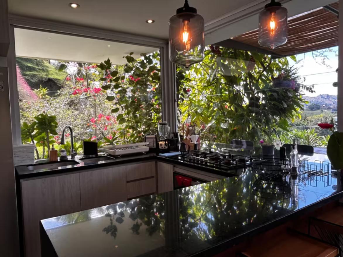 Cocina moderna de villa de lujo en Peñol con ventanales amplios y vista al jardín tropical