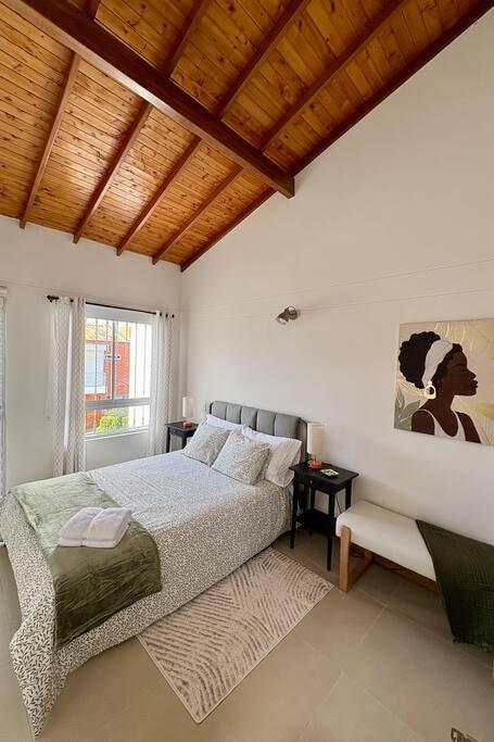 Habitación principal luminosa con cama doble, techo de madera y decoración moderna en casa en Rionegro