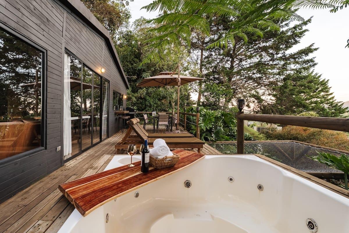 Jacuzzi exterior en terraza de madera con botella de vino y toallas en casa de Rionegro