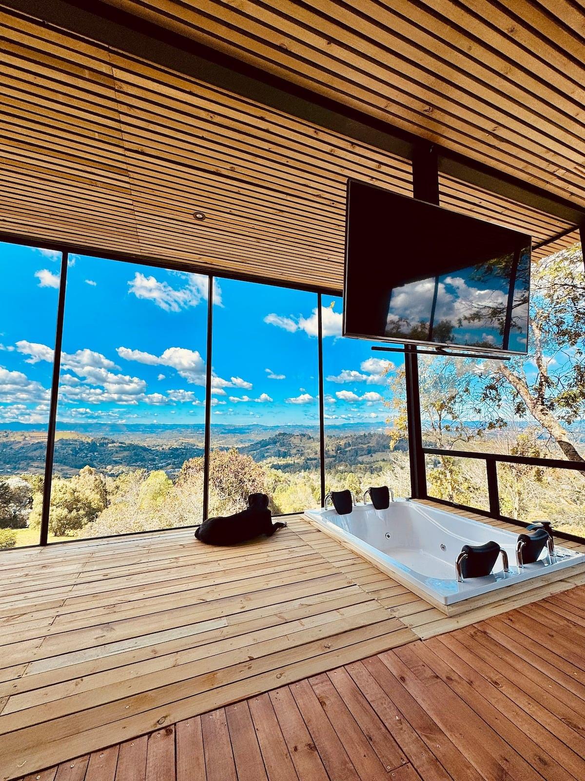 Terraza de madera con jacuzzi empotrado y televisor en casa de campo en Rionegro con vista panorámica al valle