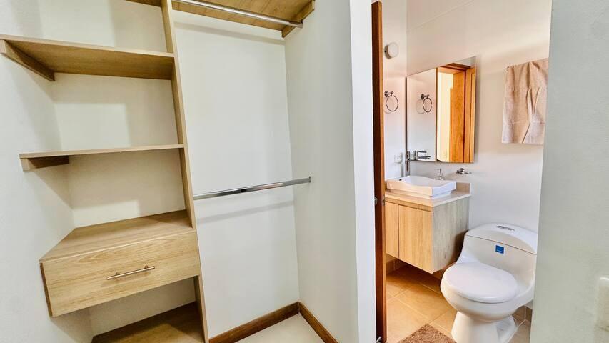 Closet de madera con estantes y cajón junto a baño privado con lavamanos y sanitario en casa en Rionegro