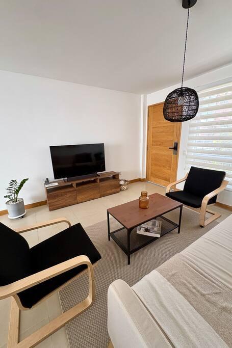 Sala de estar moderna en casa vacacional en Rionegro con sillones de madera, TV y lámpara de mimbre