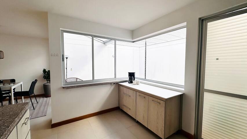 Cocina moderna con gabinetes de madera clara y ventanas amplias en casa vacacional en Rionegro