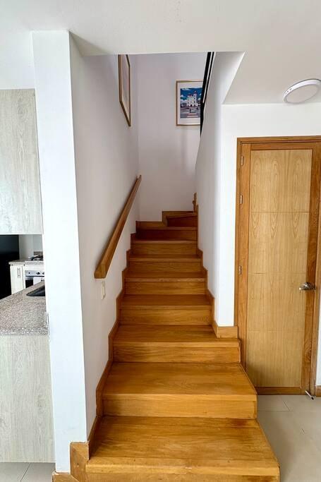 Escalera de madera en casa vacacional en Rionegro, cerca al parque de San Antonio, con barandal y paredes blancas