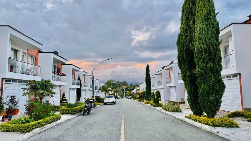 Calle residencial tranquila con casas blancas modernas y cipreses en conjunto cerrado de Rionegro, Antioquia
