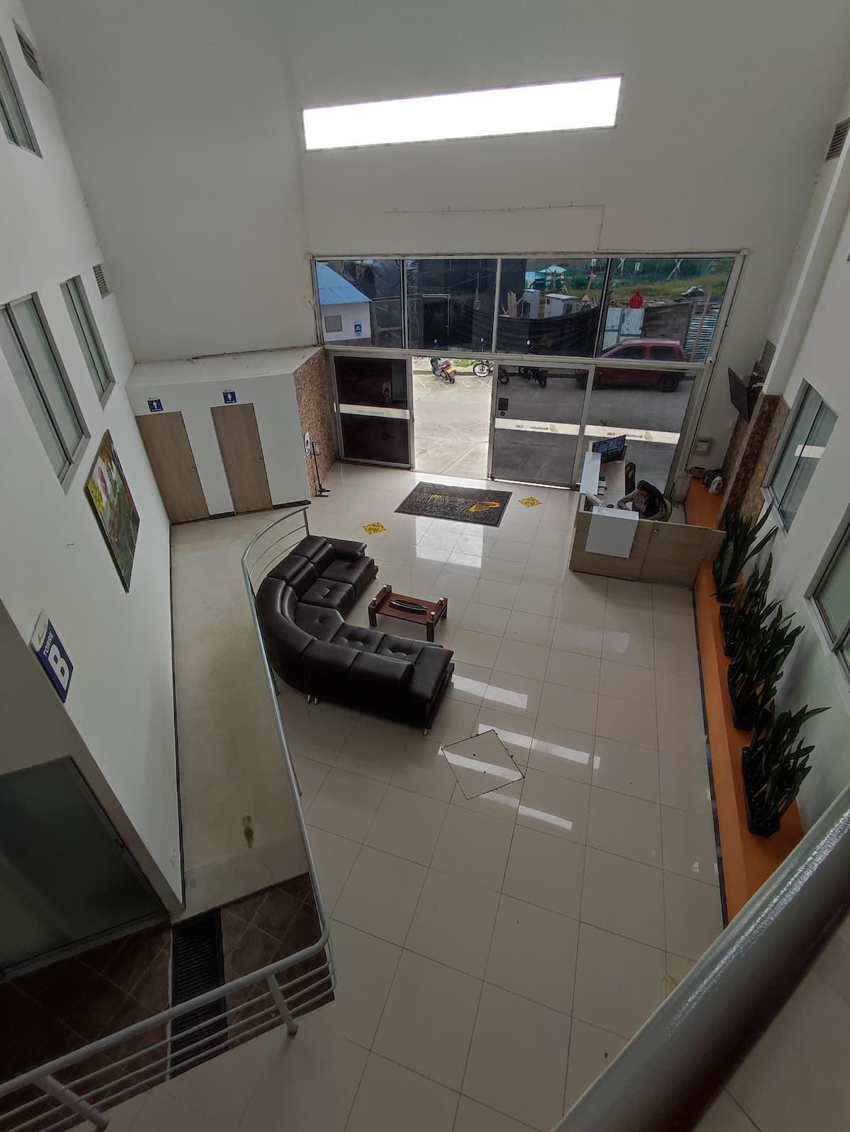 Lobby moderno con sofás negros y amplios ventanales en apartamento vacacional Montenegro Quindío