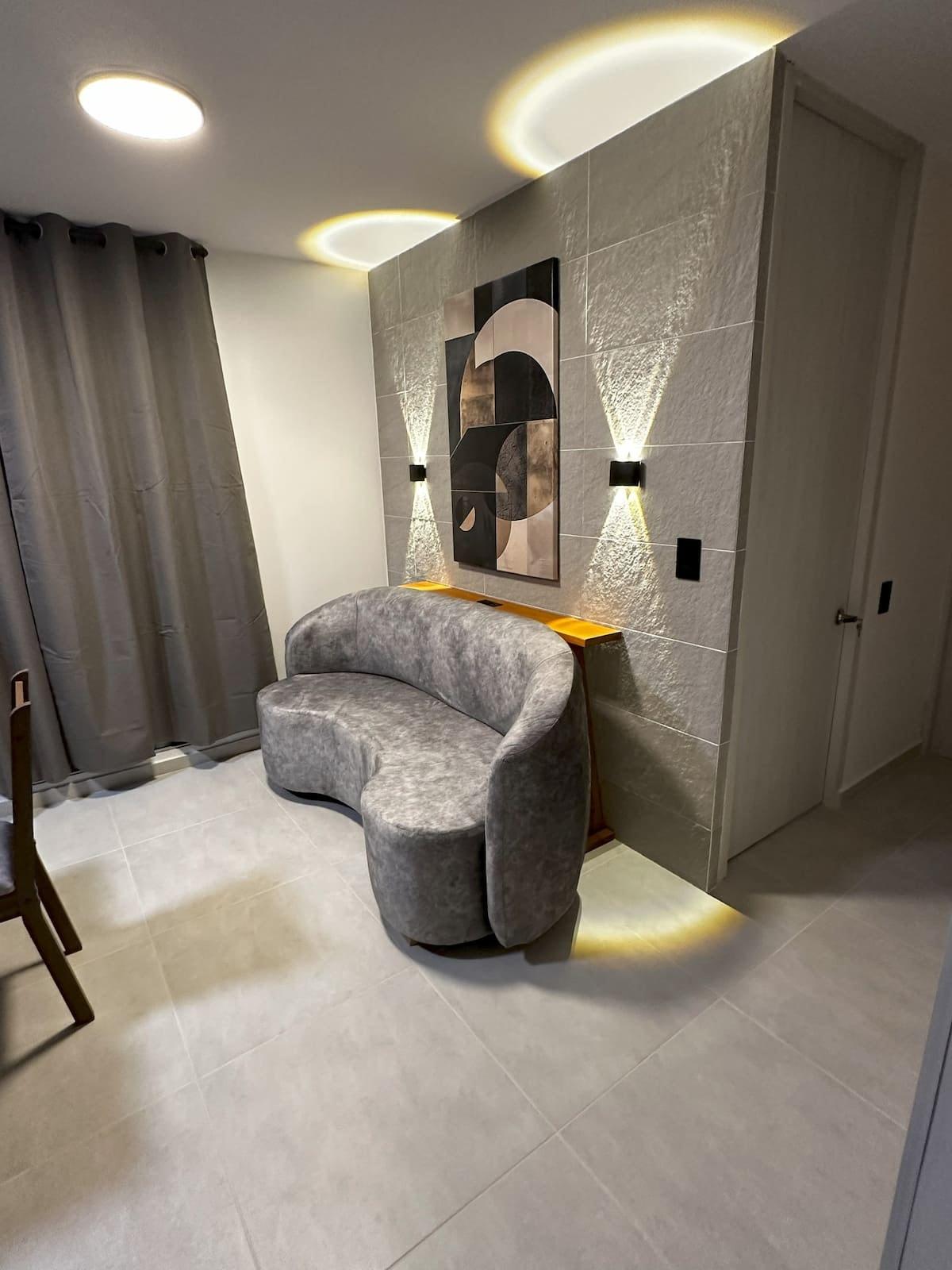Sala moderna con sillón gris y iluminación LED en apartamento Mi segunda morada en Cúcuta