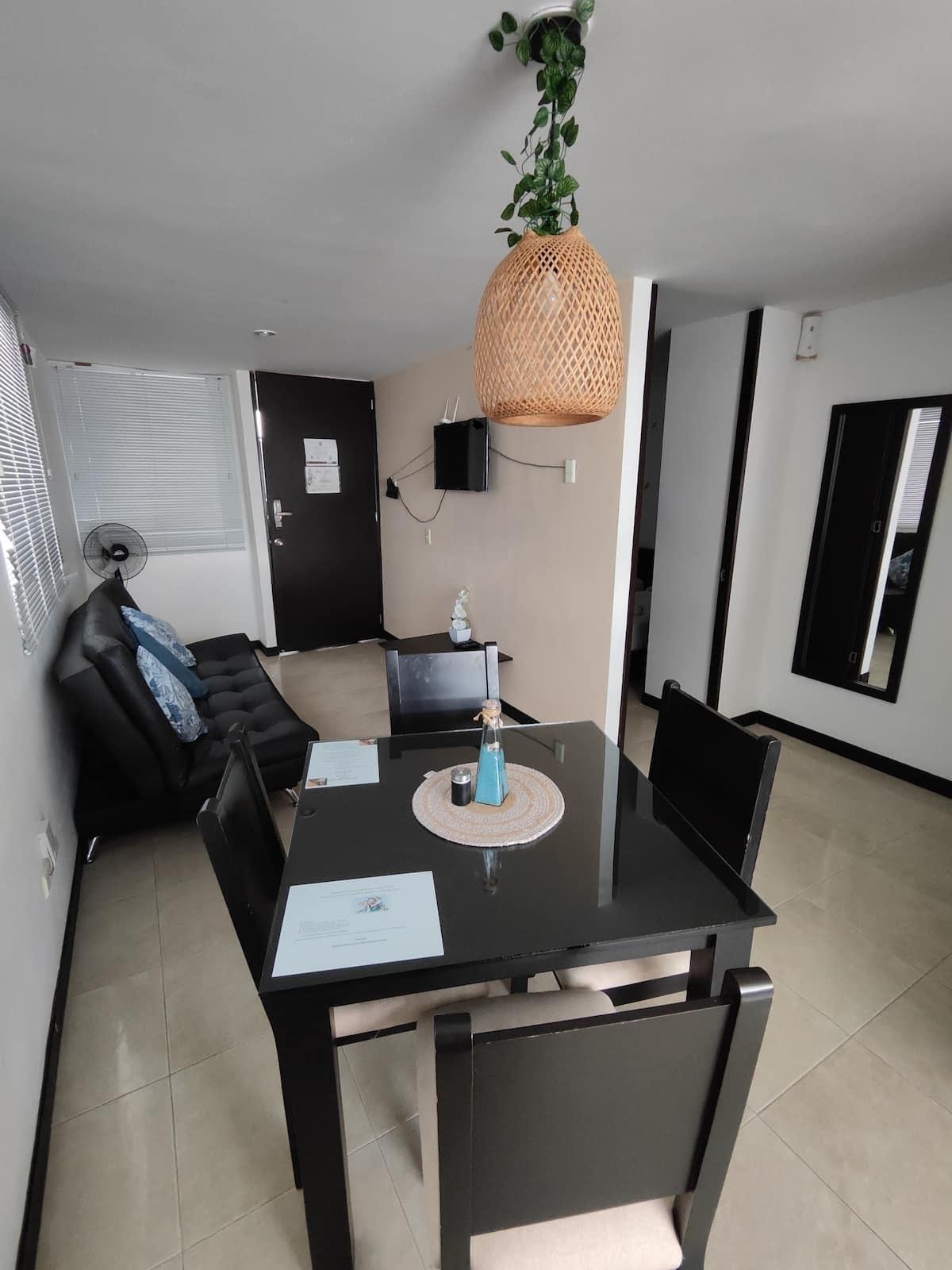Comedor moderno con mesa negra y sofá en apartamento vacacional Montenegro cerca parque del café