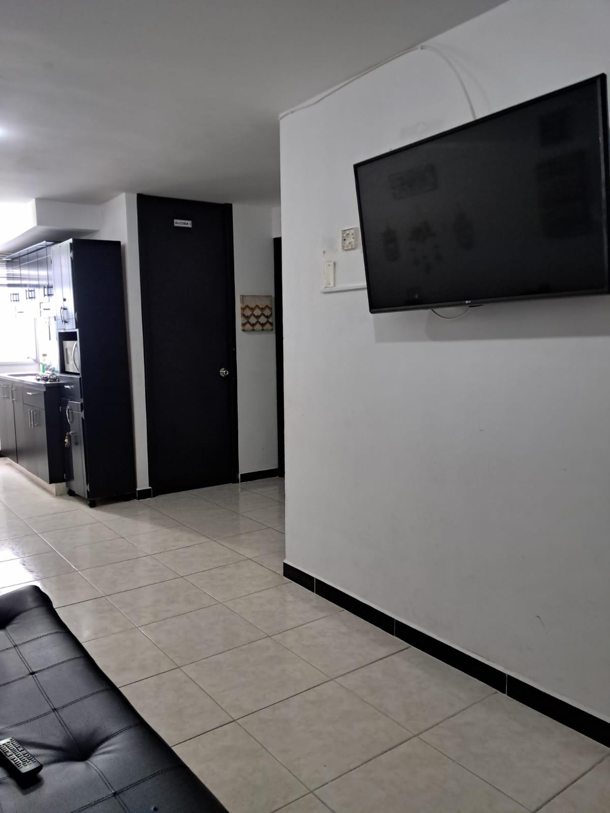Sala moderna con televisor de pantalla plana y cocina integrada en apartamento Montenegro